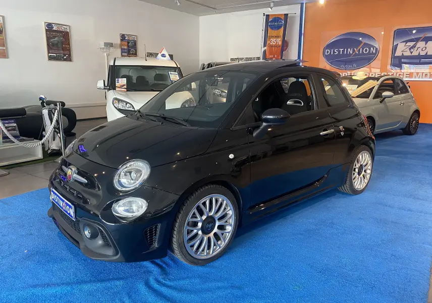 Vue 3/4 avant droite d'une ABARTH 595 noire avec jantes alliage 17 pouces et toit ouvrant électrique en showroom.