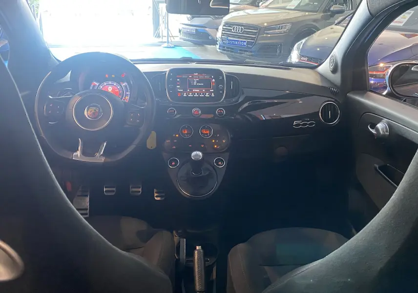 Vue intérieure avant de l'Abarth 595 noire de 2018, tableau de bord avec écran GPS et volant sport multifonctions.