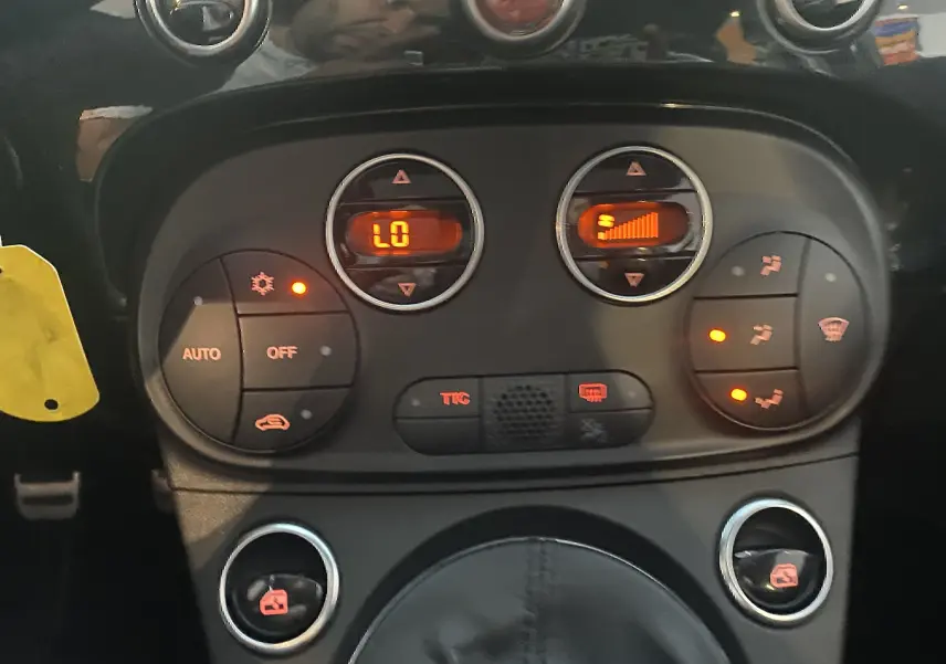 Gros plan sur la console centrale de l'Abarth 595 noire, montrant les commandes de climatisation automatique et les boutons de réglage.