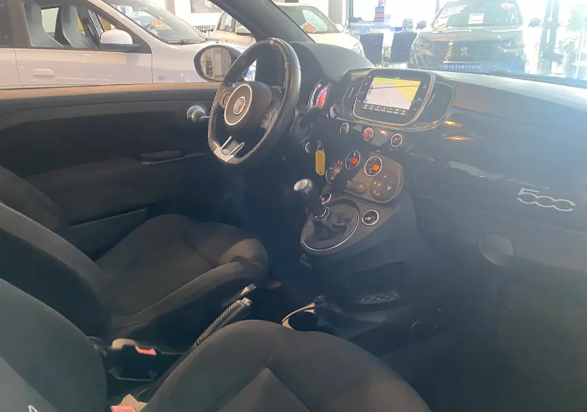 Intérieur noir de l'Abarth 595 vu côté conducteur, avec volant, tableau de bord et écran GPS allumé.