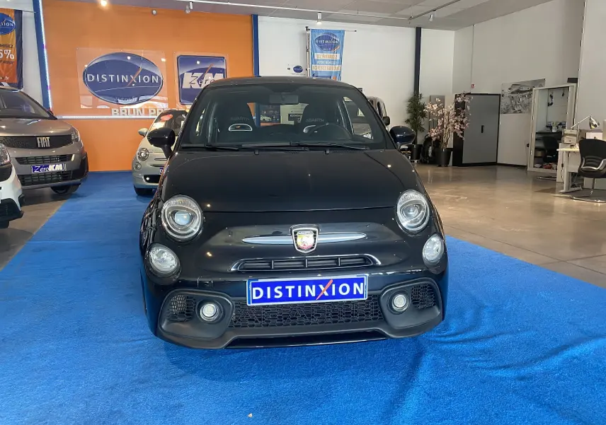 Vue frontale de l'Abarth 595 noire 2018 avec logo Abarth visible et sièges sport en intérieur showroom.