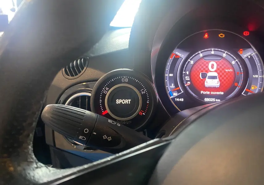 Vue rapprochée du tableau de bord de l'Abarth 595 noir, affichant le mode Sport et l'écran digital avec porte ouverte.