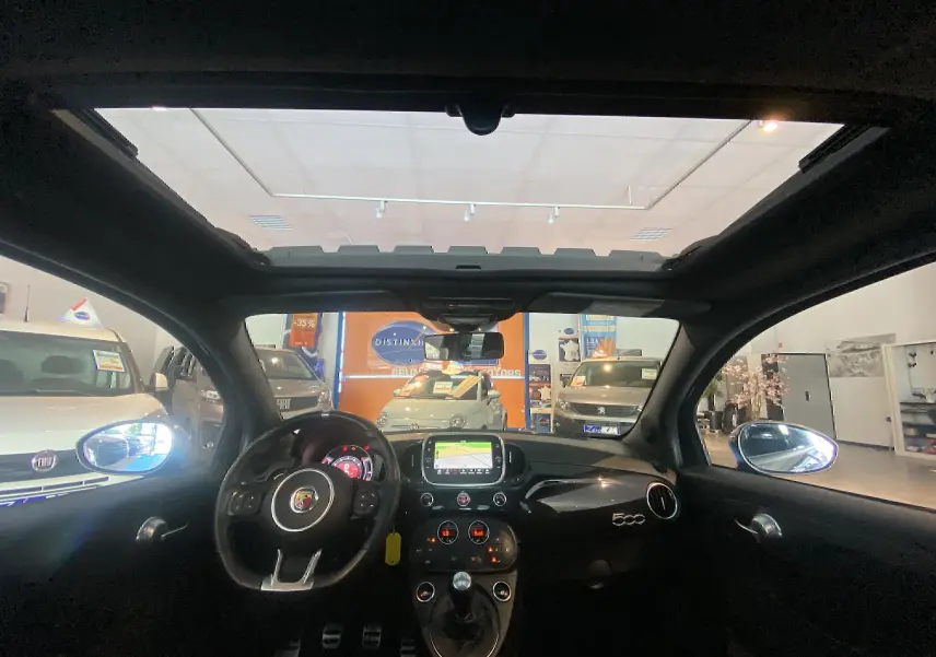 Vue intérieure avant de l'Abarth 595 noire de 2018 avec toit ouvrant électrique et tableau de bord moderne.
