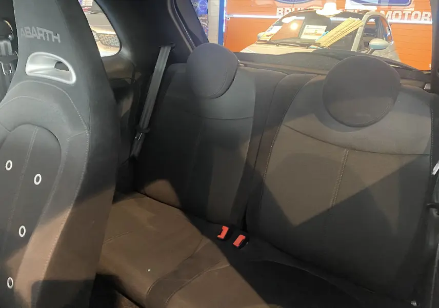 Vue intérieure arrière de l'Abarth 595 noire, montrant les sièges arrière et le dossier du siège avant avec logo Abarth brodé.