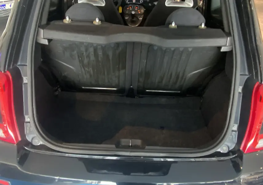 Coffre ouvert vu de l'arrière d'une ABARTH 595 noire, montrant l'intérieur du coffre et les dossiers des sièges arrière.