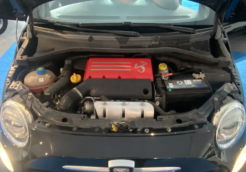 Vue avant du moteur rouge de l'Abarth 595 noire avec capot ouvert, phares ronds visibles de chaque côté.