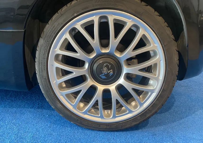 Gros plan sur la jante alu 17 pouces argentée avec logo Abarth, sur roue avant droite d'une ABARTH 595 noire