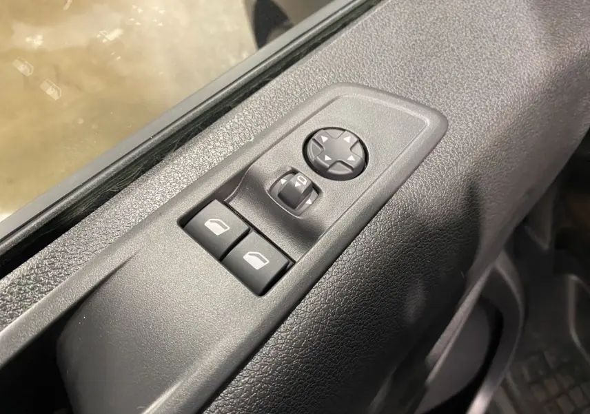 Gros plan sur les commandes de réglage des rétroviseurs et vitres côté conducteur du Citroën Jumpy Fourgon gris platinium 2024.