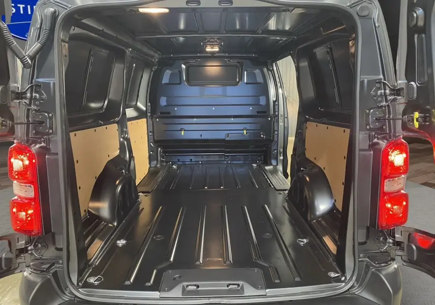 Vue arrière du Citroën Jumpy Fourgon gris platinium 2024, montrant l'espace de chargement vide et les feux arrière allumés.