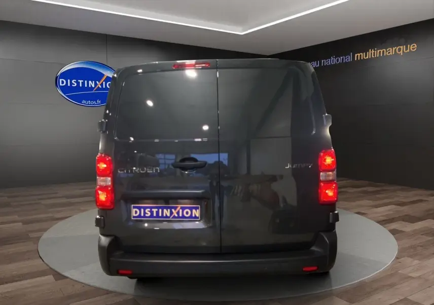 Vue arrière du Citroën Jumpy Fourgon gris platinium dans un showroom avec portes battantes fermées.