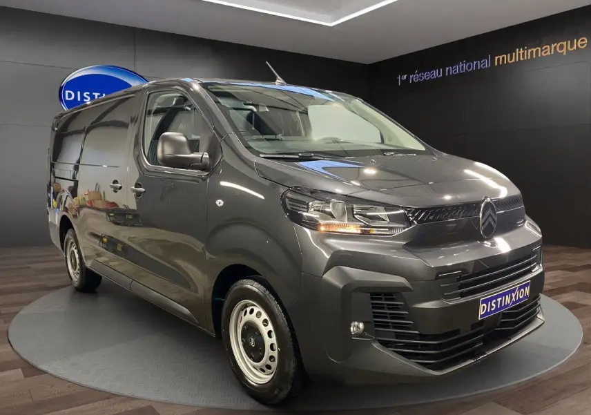 Vue 3/4 avant droit d’un Citroën Jumpy Fourgon gris platinium dans un showroom avec éclairage intérieur.