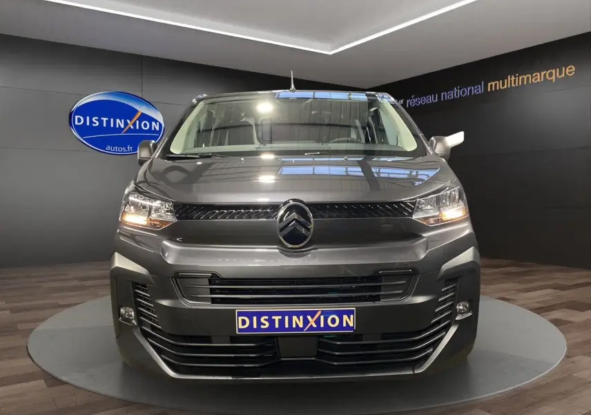 Vue frontale d'un Citroën Jumpy Fourgon gris platinium avec phares allumés et logo distinctif au centre.