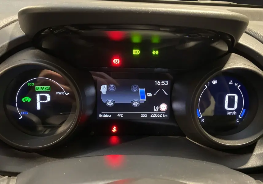 Tableau de bord numérique de Toyota Yaris Cross hybride, affichant vitesse, mode éco et indicateurs d'alerte.