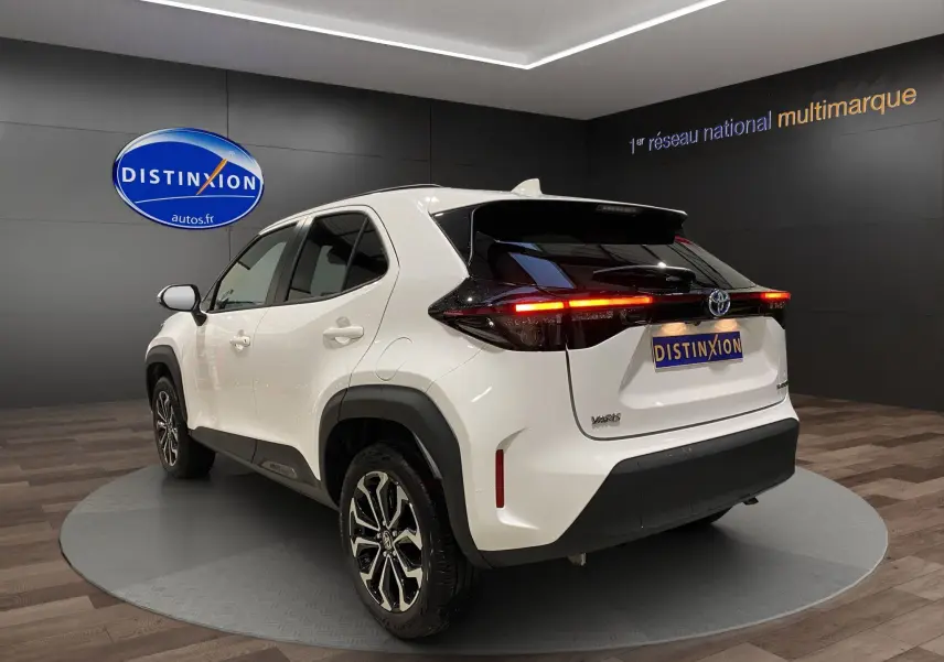 Vue 3/4 arrière droite d'une Toyota Yaris Cross blanche avec feux arrière LED allumés et jantes alu 17 pouces.