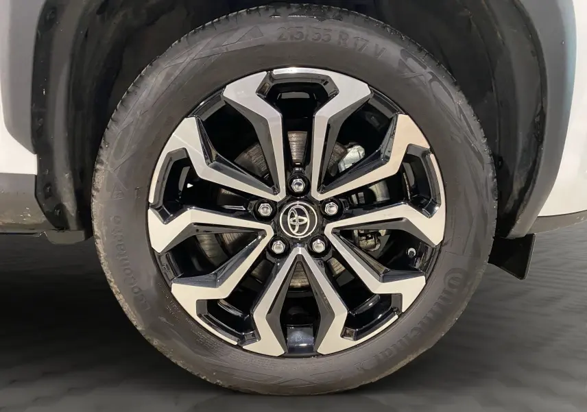 Gros plan sur la jante alu 17 pouces bicolore noir et argent de la roue avant droite d'une Toyota Yaris Cross blanche.