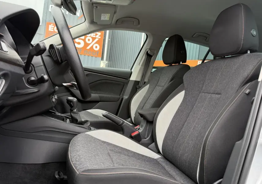Intérieur avant du Skoda Kamiq 2022, sièges tissu bicolore gris et noir avec surpiqûres orange visibles côté conducteur.