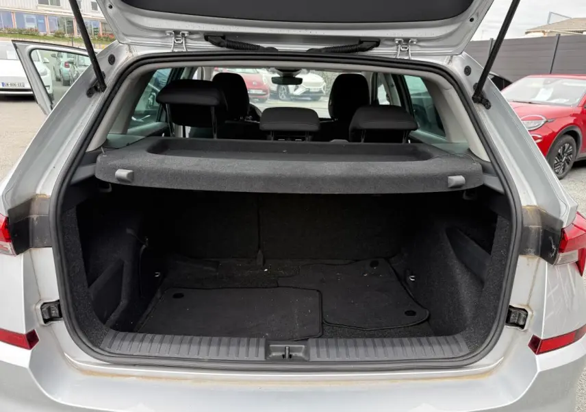 Coffre ouvert gris métallisé d'un Skoda Kamiq 2022 avec tablette cache-bagages et sièges arrière noirs visibles.