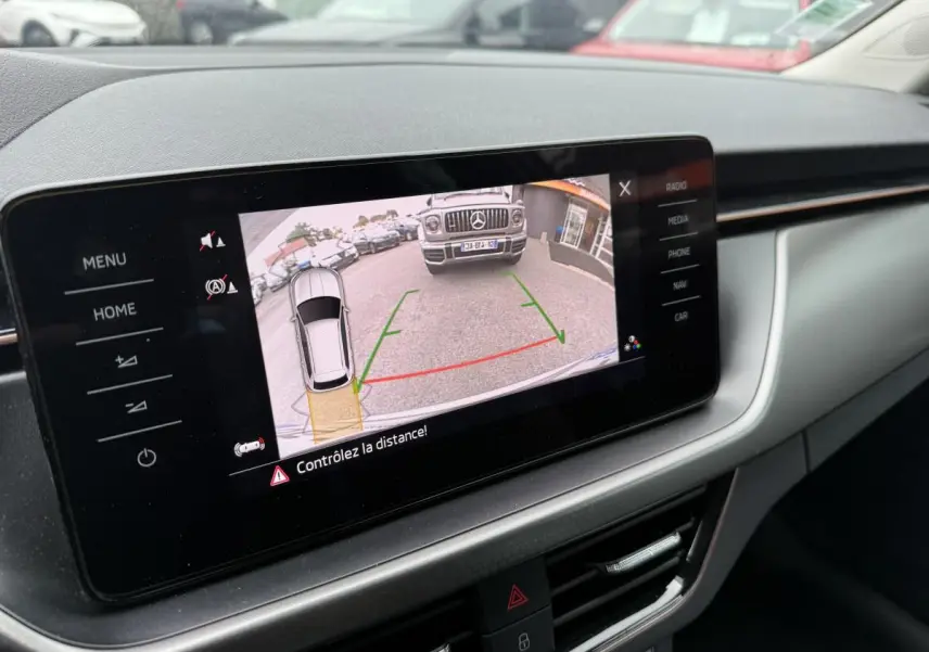 Écran tactile intérieur du Skoda Kamiq 2022 affichant la caméra de recul avec vue sur un SUV Mercedes gris devant.