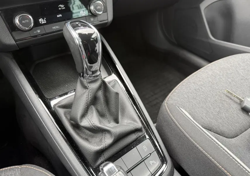 Gros plan sur la console centrale intérieure du Skoda Kamiq 2022 avec levier de vitesses automatique et sièges tissu gris.