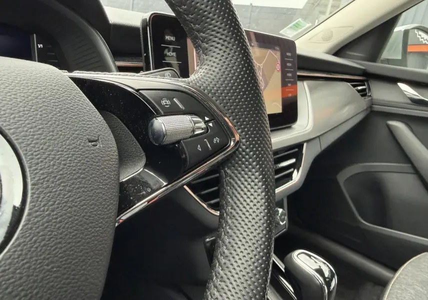 Gros plan sur le volant et la console centrale du Skoda Kamiq gris, avec écran tactile et commandes intégrées.