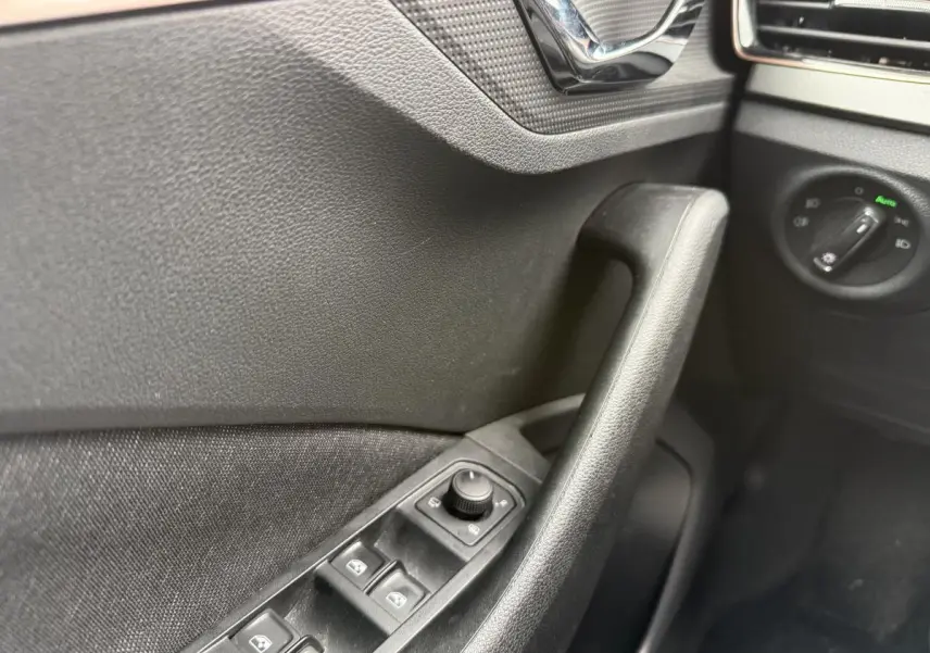 Détail de la porte côté gauche du Skoda Kamiq gris 2022, avec commandes des vitres et réglage des rétroviseurs.