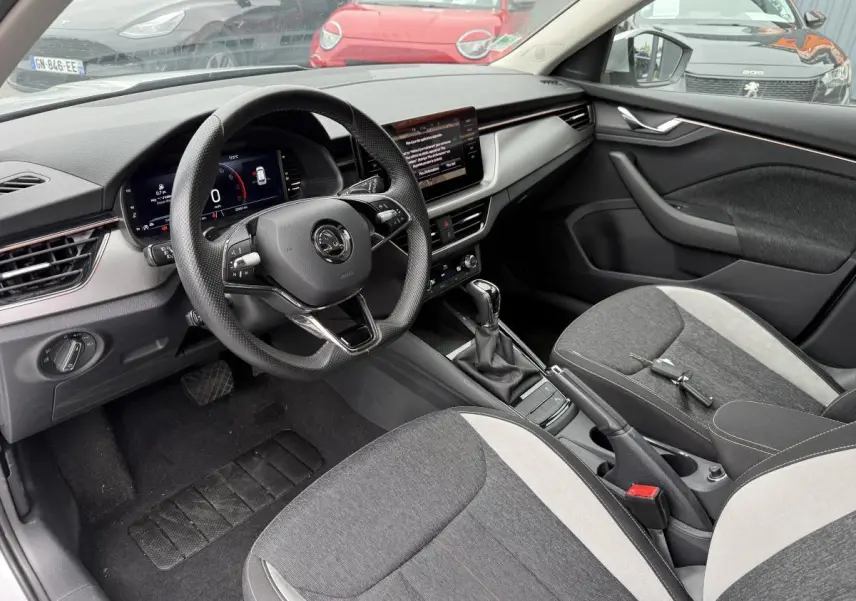 Intérieur du Skoda Kamiq 2022 vu côté conducteur, sièges tissu gris et console centrale avec boîte auto DSG7.
