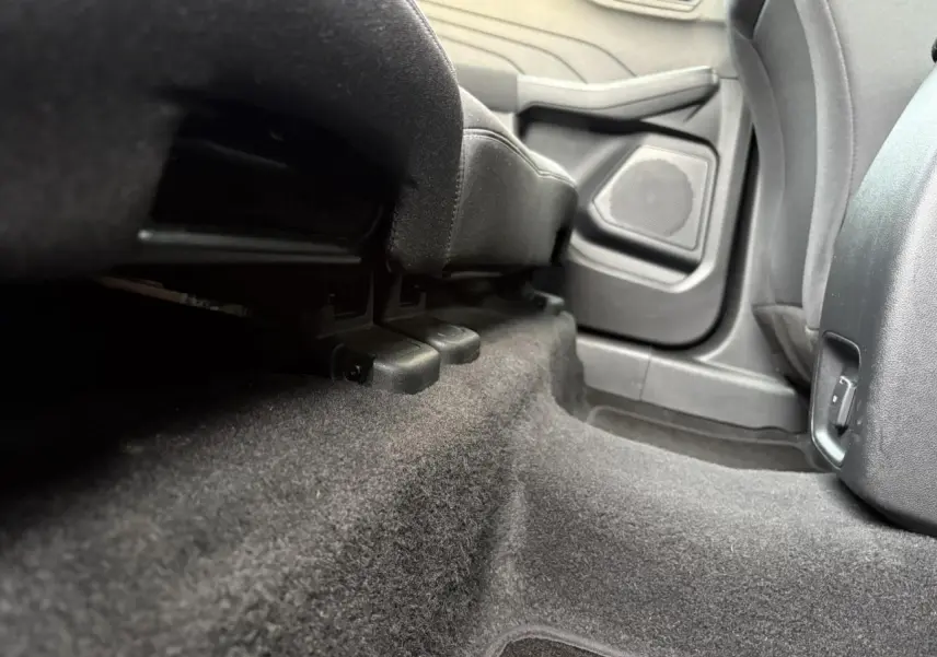 Vue en contre-plongée de l'espace au sol arrière côté droit du Ford Kuga 2024 gris Solar, montrant la moquette et la base des sièges.