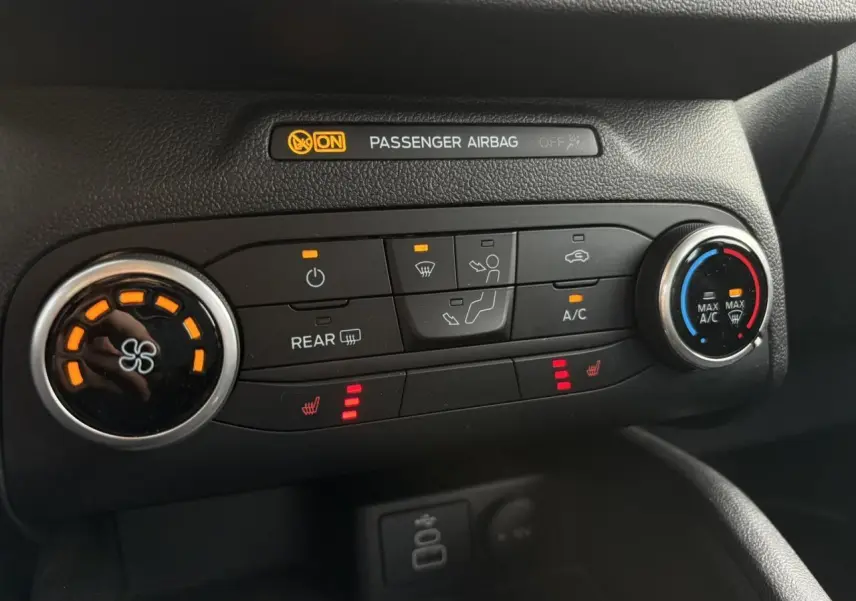 Gros plan sur la console centrale noire du Ford Kuga 2024 montrant les commandes de climatisation et sièges chauffants.