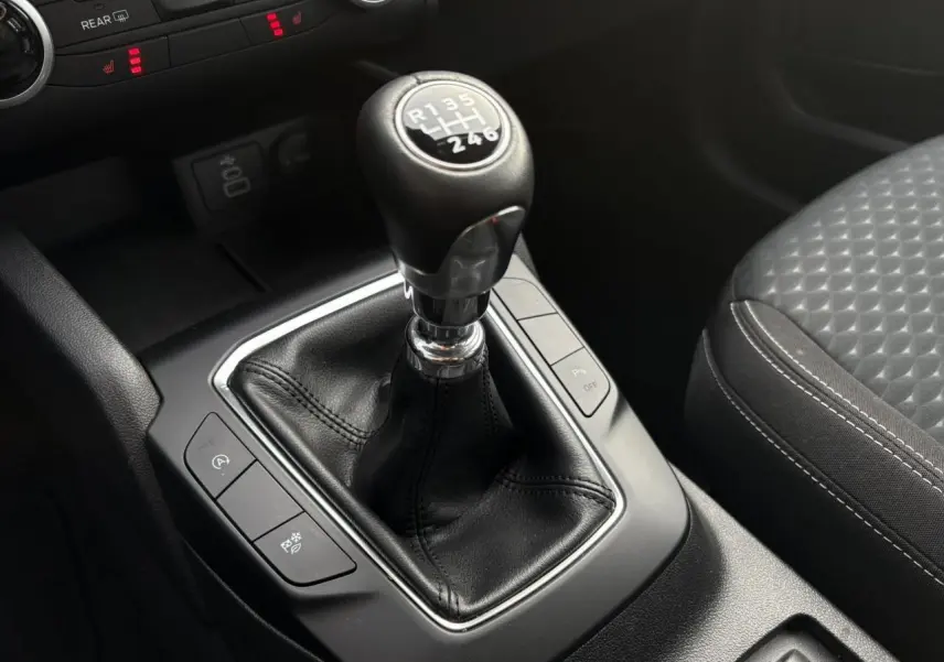 Gros plan sur le levier de vitesses manuel noir et la console centrale du Ford Kuga 2024, avec siège avant gris à motifs.