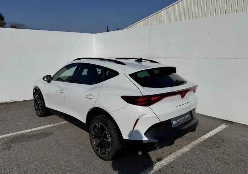 Vue 3/4 arrière droite d’un CUPRA Formentor blanc nacré avec toit noir et jantes alliage noires en extérieur.