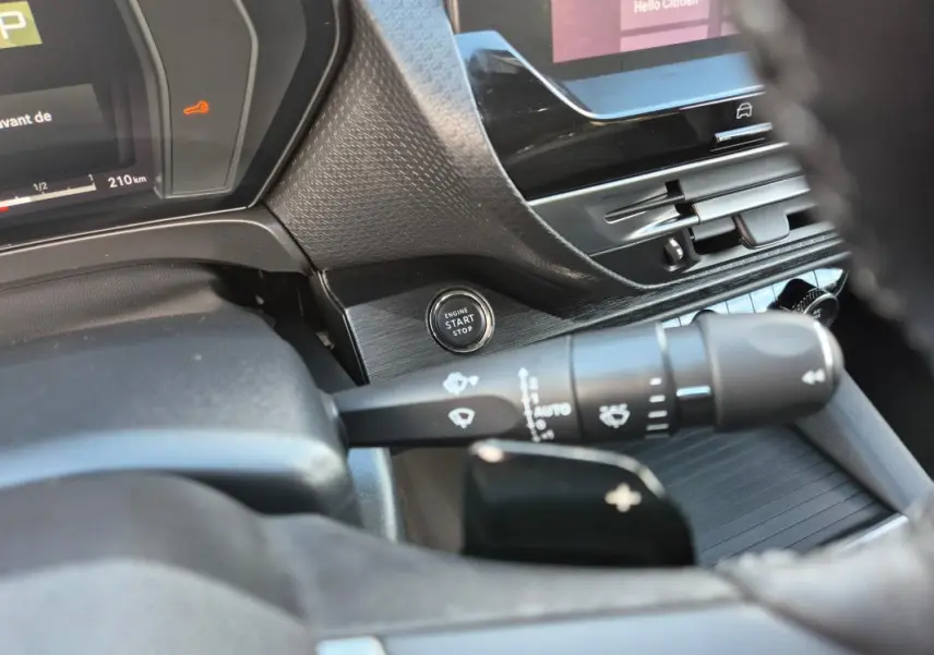 Vue rapprochée de l'intérieur du Citroën C5 X 2024, montrant le bouton start/stop et la commande d'essuie-glace côté gauche du volant cuir.