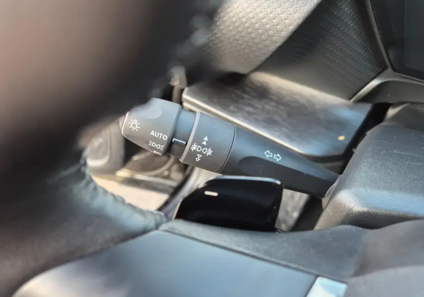 Gros plan sur la manette de commande des phares et clignotants dans l’habitacle noir d’une Citroën C5 X 2024.
