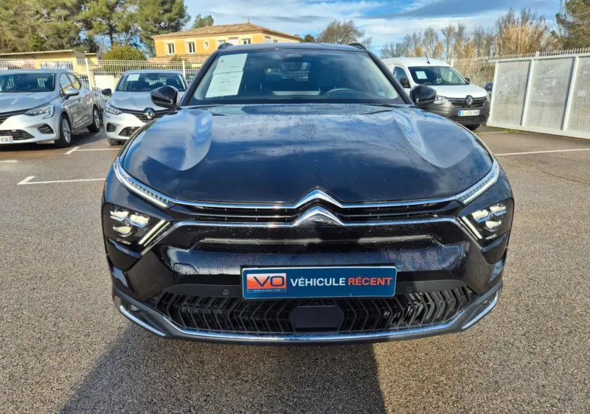 Vue avant d'une Citroën C5 X noire 2024 avec calandre chromée et feux LED distinctifs, stationnée en extérieur.