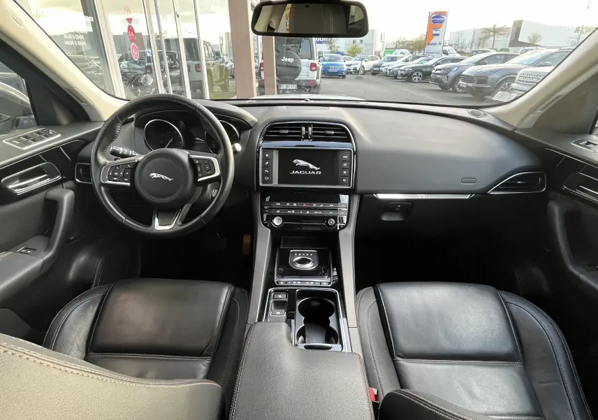 Vue intérieure avant du Jaguar F-PACE 240D Prestige 2018 avec sièges cuir noir et tableau de bord moderne.