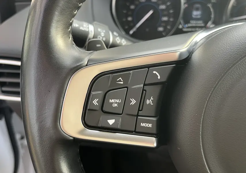 Gros plan sur les commandes gauche du volant en cuir noir du Jaguar F-PACE blanc, version 240D Prestige 2018.