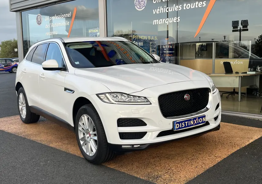 Jaguar F-PACE 240D Prestige blanc vue 3/4 avant droit devant un showroom avec calandre noire distinctive.