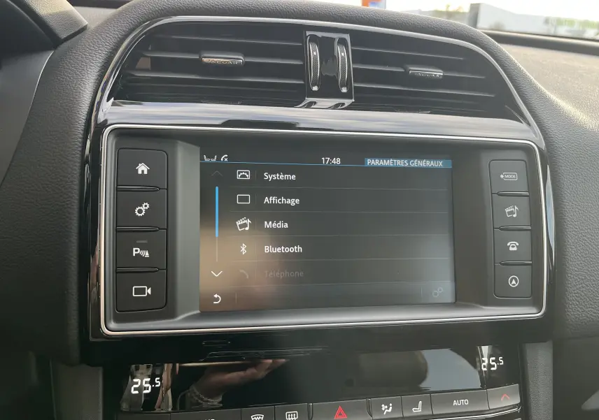 Vue rapprochée de l’écran tactile central et des commandes noires du tableau de bord du Jaguar F-PACE blanc 2018.