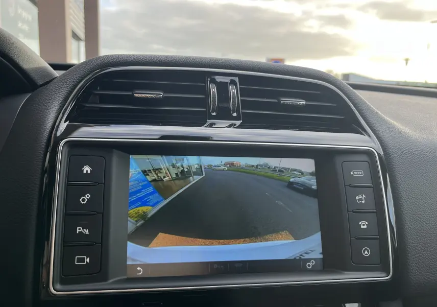 Vue intérieure du tableau de bord du Jaguar F-PACE blanc 2018, avec écran de caméra de recul affiché.