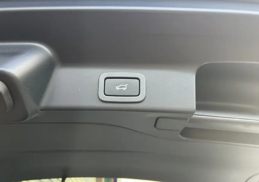 Bouton d'ouverture électrique du hayon sur la partie intérieure du coffre du Jaguar F-PACE blanc 2018.