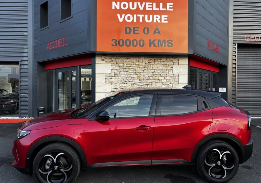 Profil droit de l'Alfa Romeo Junior rouge 2024 avec toit noir, jantes noires et détails sportifs visibles.