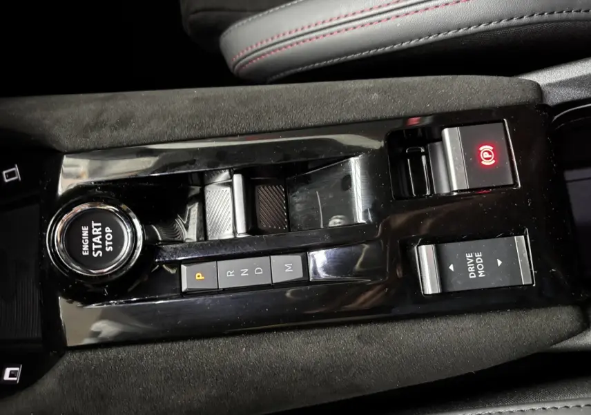 Vue rapprochée de la console centrale noire brillante de l'Alfa Romeo Junior 2024 avec boutons de démarrage, boîte auto et mode de conduite.