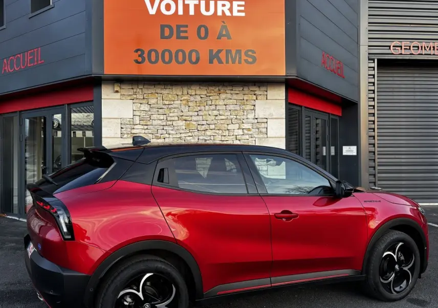 Vue de profil droit d'une Alfa Romeo Junior rouge 2024 avec toit noir et jantes noires distinctives.