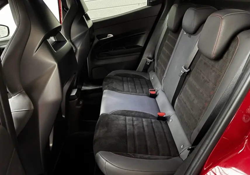 Vue intérieure côté droit des sièges arrière en cuir et alcantara noirs avec surpiqûres rouges d'une Alfa Romeo Junior rouge 2024.