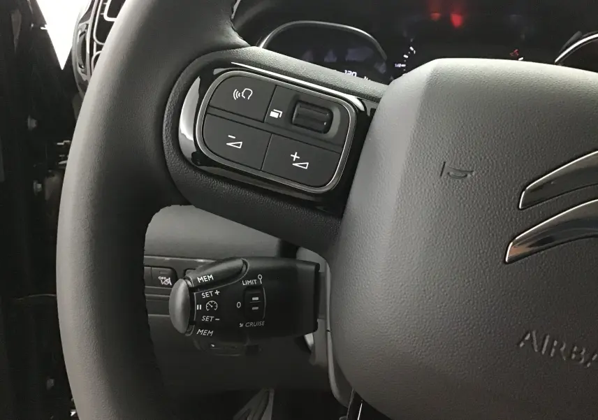 Gros plan sur le volant noir du Citroën C3 Aircross 2024, mettant en valeur les commandes intégrées à gauche.