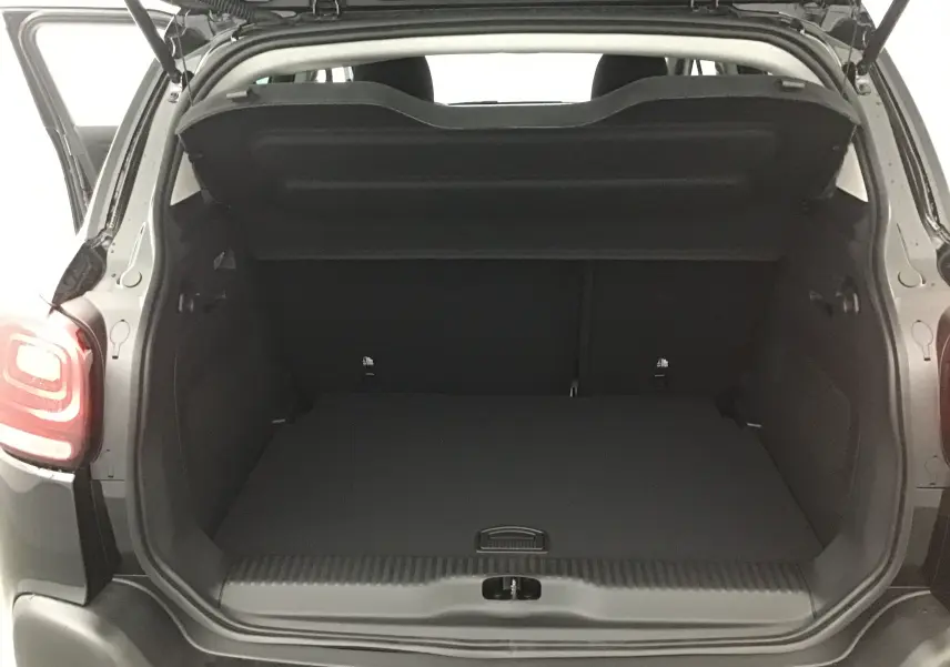 Coffre ouvert vu de l'arrière d'un Citroën C3 Aircross noir 2024 avec feux arrière allumés.