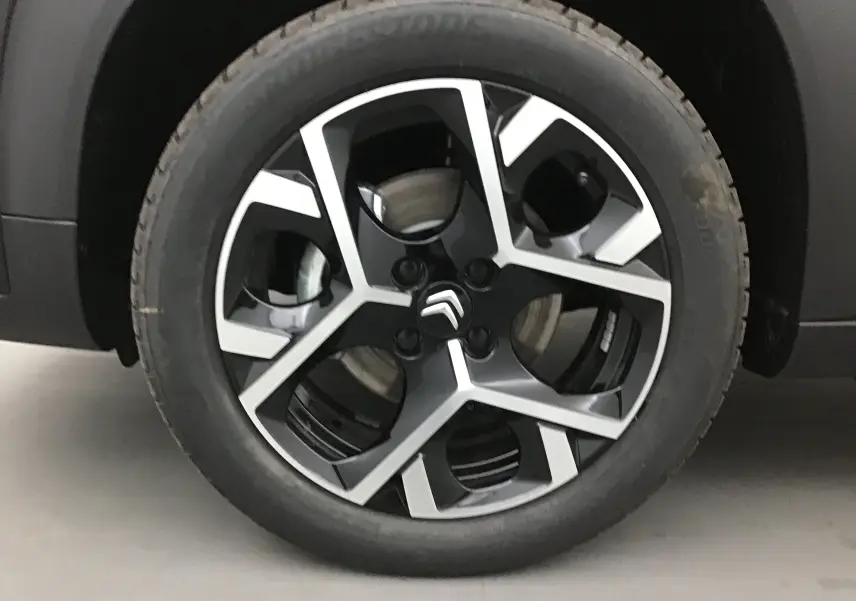 Gros plan sur la jante noire et argentée de la roue avant gauche du Citroën C3 Aircross 2024 noir.