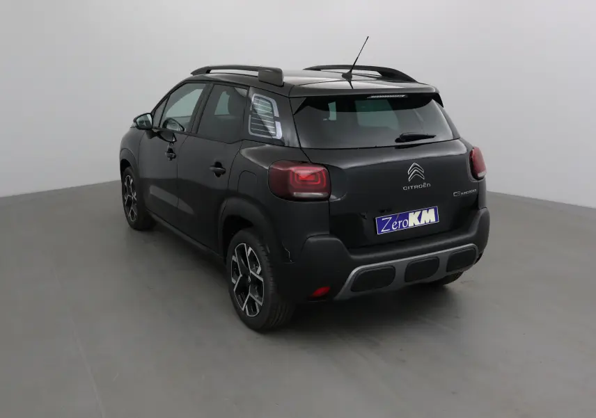 Vue 3/4 arrière gauche d'un Citroën C3 Aircross noir 2024 avec barres de toit et feux arrière LED distinctifs.