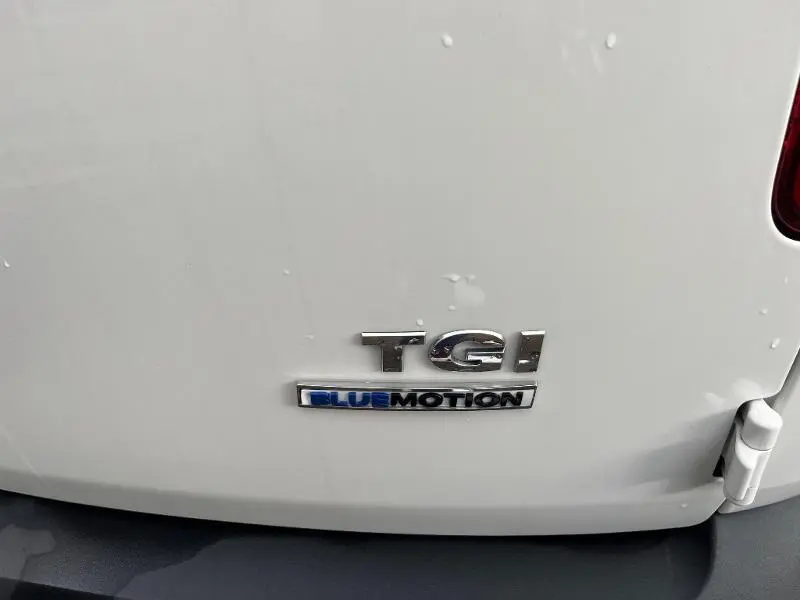 Gros plan sur l'arrière blanc d'un Volkswagen Caddy Van 1.4 TGI avec logo TGI Bluemotion visible.