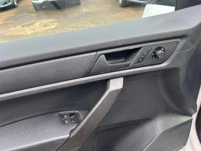 Détail de la porte intérieure côté conducteur noire du Volkswagen Caddy Van 2016 avec commandes de vitres et rétroviseurs.
