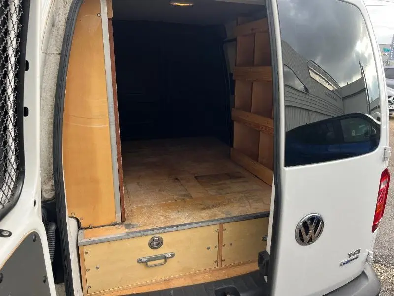 Vue arrière ouverte du Volkswagen Caddy Van blanc Candy de 2016, montrant l'espace de chargement en bois aménagé.